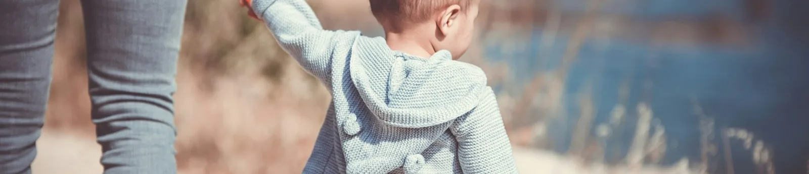 toddler's walking on the seashore with adult