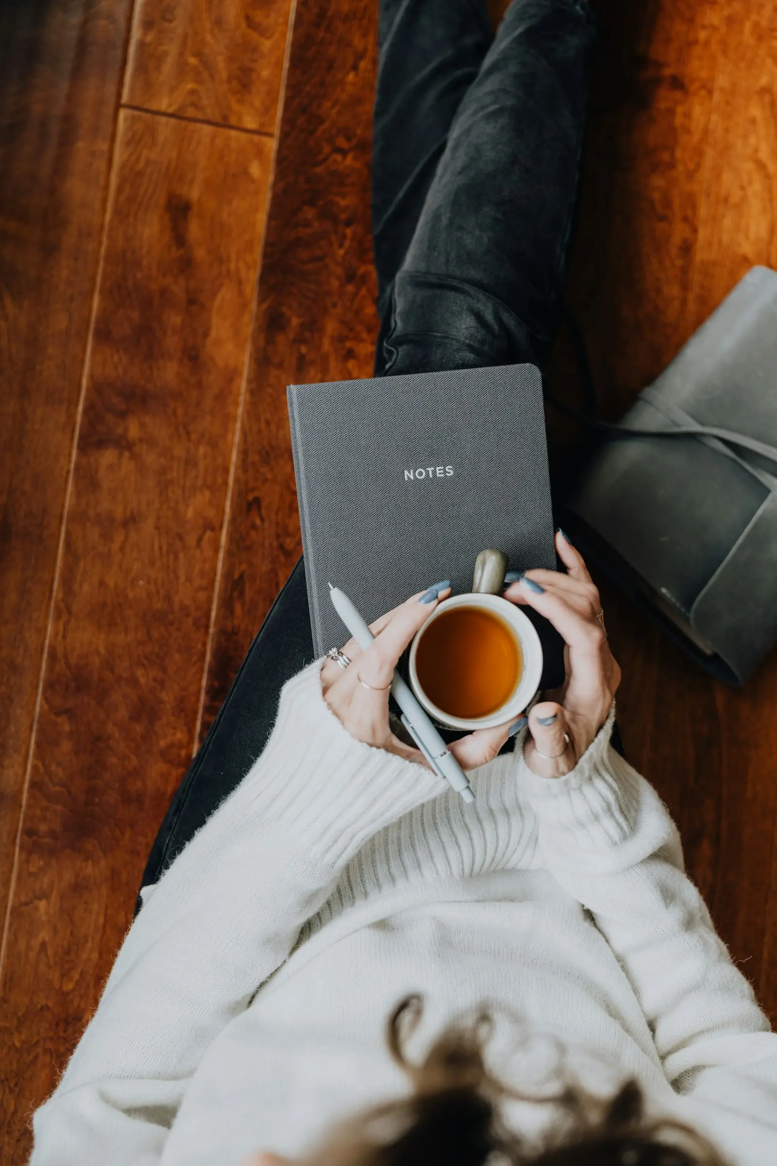 A person sitting on the floor with a laptop and a cup of coffee
